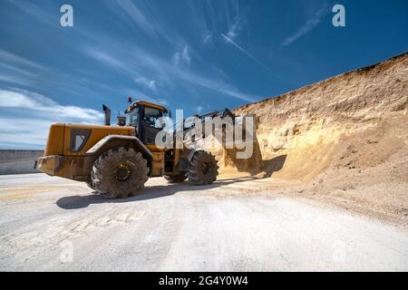 Ein Radlader trägt einen vollen Eimer mit Tierfutter. Stockfoto
