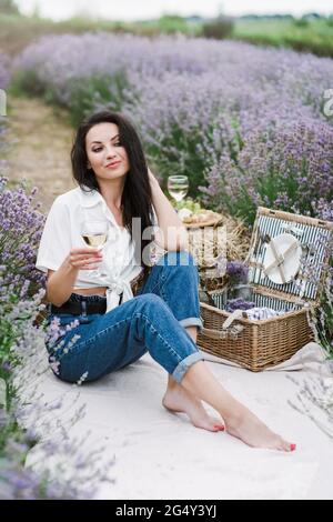 Schöne glückliche Frau entspannend und genießen ein Glas Wein in Lavendel Feld. Stockfoto