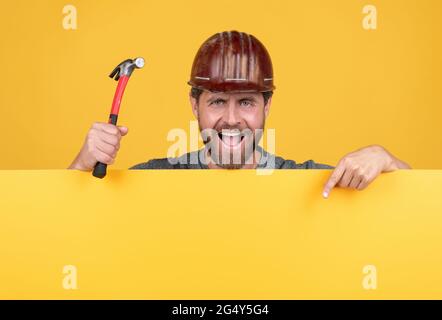 Glücklicher Tag der Geburt. Reifer Mann im Helm mit Hammer. builder Point Finger auf Kopie Raum Stockfoto