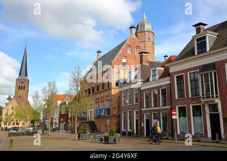 FRANEKER, NIEDERLANDE - 16. MAI 2021: Die mittelalterliche Fassade des Museums Martena und der Uhrenturm von Martinikerk (St. Martin Kirche) auf der rechten Seite Stockfoto