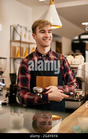 Fröhlicher männlicher Kellner im Vorfeld im Café Stockfoto