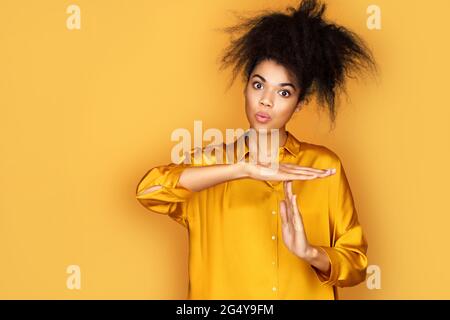 Ich brauche Pause. Mädchen macht eine Geste der Zeitüberschreitung. Foto von afroamerikanischen Mädchen auf gelbem Hintergrund Stockfoto