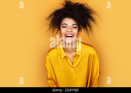 Überfröhliches Mädchen kann nicht aufhören zu lachen. Foto von afroamerikanischen Mädchen auf gelbem Hintergrund Stockfoto