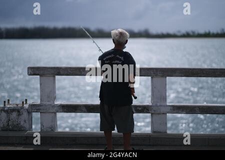 Ein älterer Thailänder fischt von einer hohen Brücke aus Stockfoto