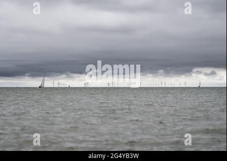 Die Kraft des Windes: Segelboote und Windkraftanlagen nutzen Wind im Offshore-Windpark Kentish Flats in der Themsemündung, Kent, England. Stockfoto
