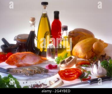 Fünf Glasflaschen mit farbigen Flüssigkeiten rohe Zutaten Geflügel, Fischgarnelen, Knoblauchpilze, rote Paprika Stößel und Mörser auf weißem Kopierplatz Stockfoto