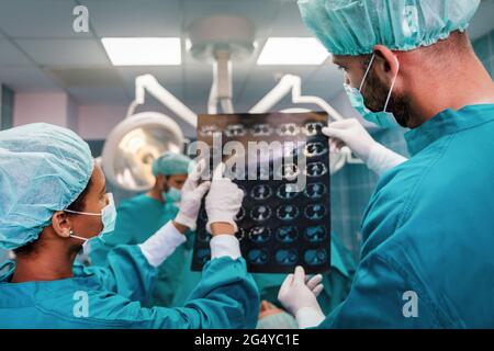 Gesundheitswesen und medizinisches Konzept. Gruppe von Ärzten, die Röntgenaufnahmen vor der Operation betrachten Stockfoto