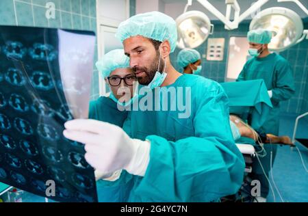 Gesundheitswesen und medizinisches Konzept. Gruppe von Ärzten, die Röntgenaufnahmen vor der Operation betrachten Stockfoto