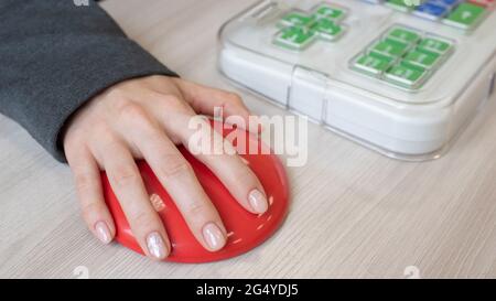 Frau mit zerebraler Lähmung, die an einer speziellen drahtlosen Computermaus arbeitet. Stockfoto