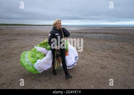 Die Paramotoristin Sacha Dench mit ihrem adaptierten elektrischen Paramotor überprüft das Wetter am Strand von Stevenston, um zu sehen, ob die Bedingungen für den Flug stimmen. Bilddatum: Donnerstag, 24. Juni 2021. Stockfoto