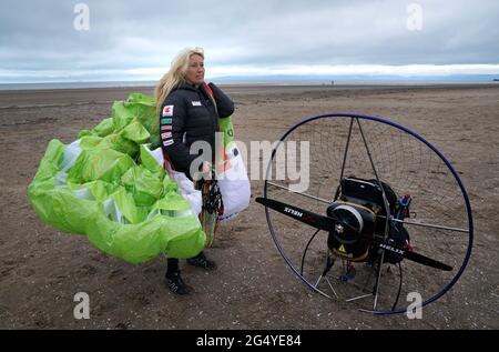 Die Paramotoristin Sacha Dench mit ihrem adaptierten elektrischen Paramotor überprüft das Wetter am Strand von Stevenston, um zu sehen, ob die Bedingungen für den Flug stimmen. Bilddatum: Donnerstag, 24. Juni 2021. Stockfoto