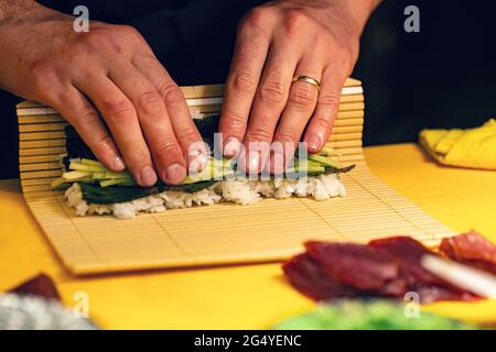 Chefhand bereitet japanisches Essen zu, Chefkoch macht Sushi, bereitet Sushi-Rollen zu Stockfoto