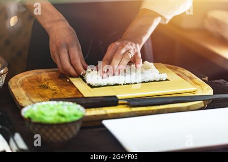 Koch bereitet japanische Sushi-Brötchen zu. Prozess der Herstellung von Sushi Stockfoto