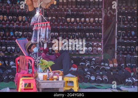 Phnom Penh, Kambodscha. 24. Juni 2021. Seit 4 Monaten kämpft Phnom Penh mit einem COVID - 19 Anstieg. Ein Schuhverkäufer, der eine schützende Gesichtsmaske/Abdeckung trägt, wartet während der Coronavirus-Pandemie auf Kunden. Quelle: Kraig lieb / Alamy Live News Stockfoto