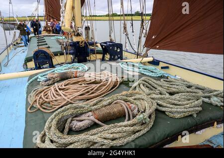 Verschiedene Seile, die auf der Abdeckung des historischen Segelschiffes „Edith May“ in der Themsemündung in Kent, England, aufgestellt wurden. Crew und Passagiere im Hintergrund. Stockfoto