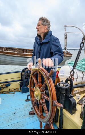 Sichere Hände: Passagier auf dem historischen Segelschiff „Edith May“ als amtierender Skipper auf einer Reise in die Themse-Mündung, Kent, England. Stockfoto