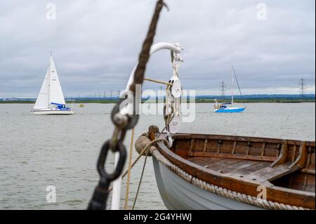 Zwei Segelboote an der Themsemündung vom historischen Segelschiff „Edith May“ aus gesehen, dessen Beiboot im Vordergrund steht. River Medway, Kent, England. Stockfoto