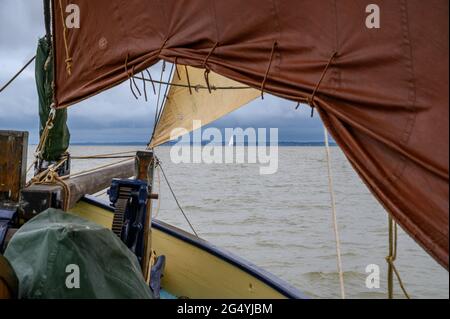 Ein entferntes Segelboot, das von unter der Vorsehung und dem Jib auf dem Bug des historischen Segelschiffs „Edith May“ in der Themse-Mündung, Kent, England, gesehen wird. Stockfoto