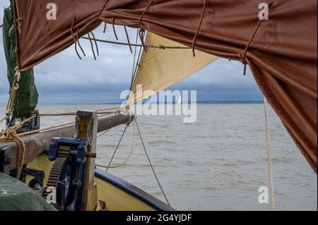 Ein entferntes Segelboot, das von unter der Vorsehung und dem Jib auf dem Bug des historischen Segelschiffs „Edith May“ in der Themse-Mündung, Kent, England, gesehen wird. Stockfoto