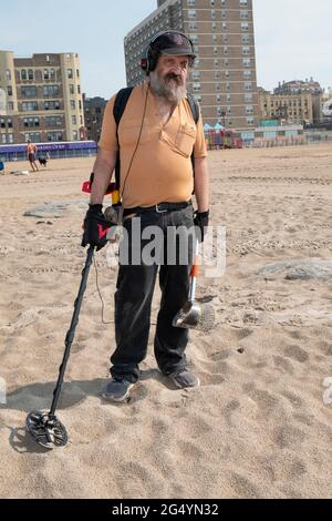 Früh am späten Frühlingsmorgen durchstreift ein Mann den Sand von Brighton Beach auf der Suche nach Münzen und versteckten Schätzen. In Brooklyn, New York City. Stockfoto