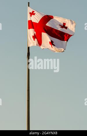 Die Flagge Georgiens winkt auf einem Fahnenmast vor Himmelshintergrund Stockfoto