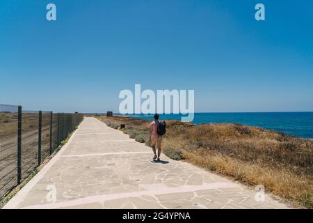 Thema der Erkundung der Insel Zypern zu Fuß. Mann mit Rucksack ist Spaziergänge am Meer entlang der Küste Broadwalk in der Stadt Paphos auf Zypern im Sommer Stockfoto