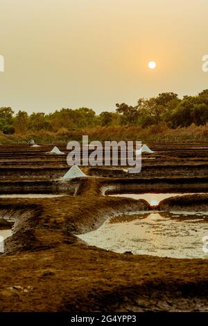 Wunderschöne Aufnahme von Salzverdunstungspeichen vor dem Hintergrund des orangefarbenen Sonnenuntergangs Stockfoto