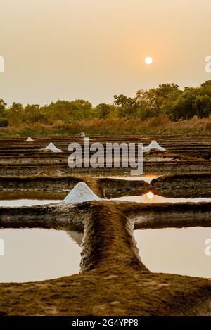 Wunderschöne Aufnahme von Salzverdunstungspeichen vor dem Hintergrund des orangefarbenen Sonnenuntergangs Stockfoto