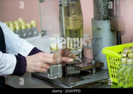 Arbeiter Hände und leere Flaschen auf einem Förderband bei der Herstellung von alkoholischen Getränken. Stockfoto