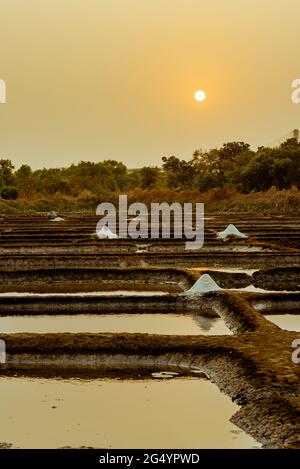 Wunderschöne Aufnahme von Salzverdunstungspeichen vor dem Hintergrund des orangefarbenen Sonnenuntergangs Stockfoto
