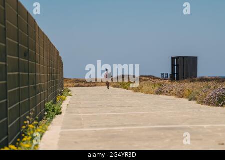 Mann Tourist mit Rucksack Spaziergang entlang Wanderweg an der felsigen Küste des Mittelmeers in der Stadt Paphos von Zypern im Sommer sonnig heißes Wetter. Küste Stockfoto