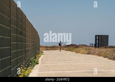 Mann Tourist mit Rucksack Spaziergang entlang Wanderweg an der felsigen Küste des Mittelmeers in der Stadt Paphos von Zypern im Sommer sonnig heißes Wetter. Küste Stockfoto