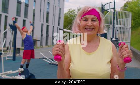 Ältere Frau Großmutter Athlet tun Routine Gewichtheben Hanteln Übungen auf dem Spielplatz Stockfoto