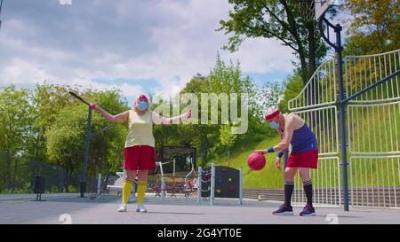 Aktive ältere Frau spielt während des Coronavirus im Freien auf dem Sportspielplatz Basketball Stockfoto