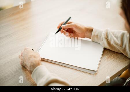 Cacausian Mann Hände Schreiben in einem leeren Papier Notizbuch mit einem Stift, Projektplanung, eine Shopping-oder To-Do-Liste. Platz für Text im Notizblock Stockfoto