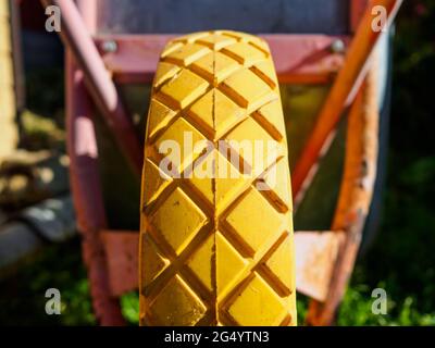 Selektiver Fokus auf die Lauffläche des gelben Rades des Gartenwagens. Unscharfer Hintergrund. Sommersonntag. Stockfoto