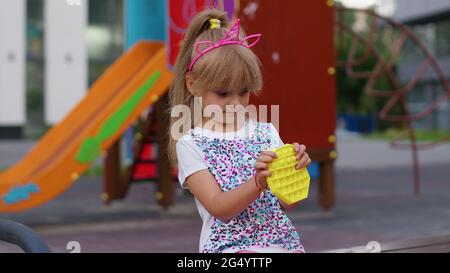 Kinder Mädchen quetschen drückt bunte Anti-Stress-Touchscreen-Push Pop es beliebtes Spielzeug im Park Stockfoto