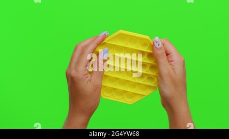 Mädchen Hände quetschen drückt bunte Anti-Stress-Touchscreen drücken Pop it Spielzeug Spiel auf Chroma-Taste Stockfoto