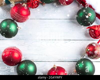 Weihnachtliche rote und grüne Ornamente mit Geschenken und weihnachtsmütze auf Holztisch. Festliche Grußkarte Stockfoto