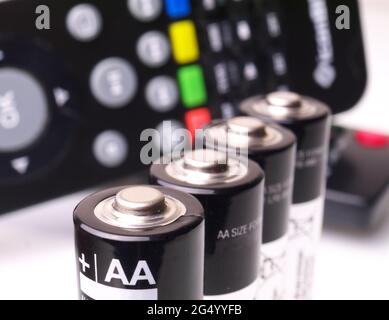 Vier AA-Batterien hintereinander vor der Fernbedienung, Makro, geringe Schärfentiefe Stockfoto