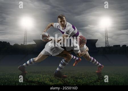 Zwei professionelle männliche Rugby-Spieler spielen isoliert auf Stadionhintergrund. Konzept von Sport, Action, Bewegung, Wettkampf. Stockfoto
