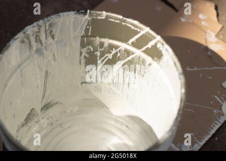 Ein Eimer mit weißer Farbe. Behälter mit Lackfarbe. Details der Reparaturen im Hof. Stockfoto
