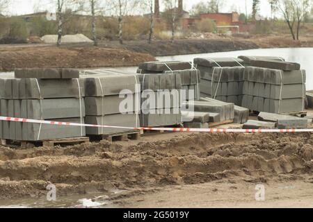 Viele Bordsteine auf der Baustelle. Steinblöcke für die Straße. Erstellen von Parkspuren. Randstein. Stockfoto