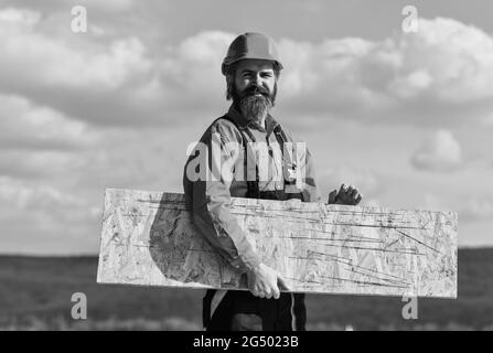 Holzwerkstoff. Provisorische Ausrüstung oder Strukturen montieren. Renovierungsservice. Mann trägt Faserplatten. Faserplatten in Wohn- und Stockfoto