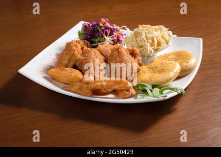 In Teig gebratenes Hühnerfilet auf einem Teller mit Kartoffeln, Brot und Salat Stockfoto