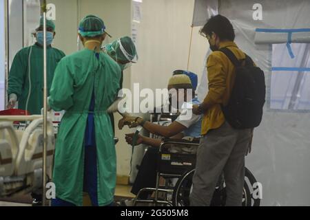 Jakarta, Indonesien. Juni 2021. Medizinische Mitarbeiter in Schutzanzügen überprüfen den Zustand eines COVID-19-Patienten in einem temporären Tierheim in einem Krankenhaus in Jakarta, Indonesien, 24. Juni 2021. Quelle: Agung Kuncahya B./Xinhua/Alamy Live News Stockfoto