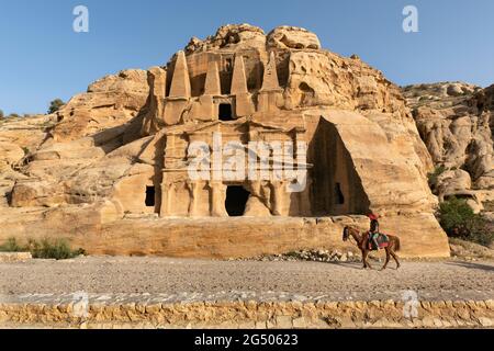 Touristenüberquerung des Obelisken-Grabes und des Bab Al-Siq Triclinium zwischen dem Petra Besucherzentrum und dem Eingang zum Siq. Stockfoto