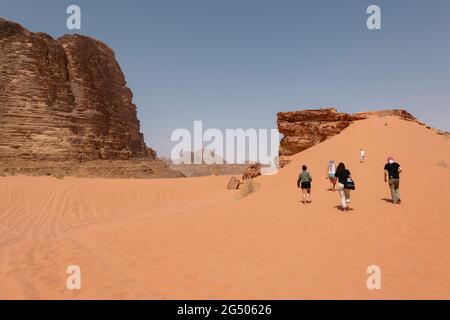 Touristen, die das Wadi Rum Schutzgebiet erkunden. Wadi Rum oder Valley of the Moon ist berühmt für seine atemberaubende Wüstenlandschaft, Wüstentäler und Dünen. Stockfoto