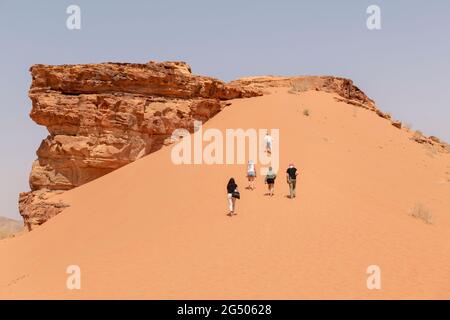 Touristen, die das Wadi Rum Schutzgebiet erkunden. Wadi Rum oder Valley of the Moon ist berühmt für seine atemberaubende Wüstenlandschaft, Wüstentäler und Dünen. Stockfoto