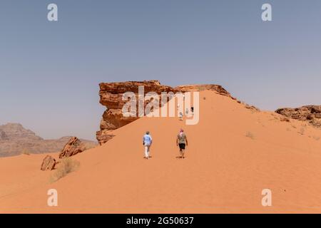 Touristen, die das Wadi Rum Schutzgebiet erkunden. Wadi Rum oder Valley of the Moon ist berühmt für seine atemberaubende Wüstenlandschaft, Wüstentäler und Dünen. Stockfoto